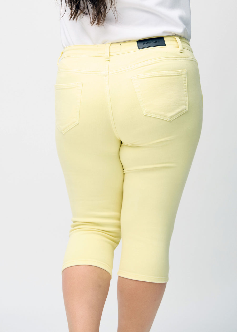 Lysegule skinny capris set bagfra tæt på en plus-size model for at vise detaljer.