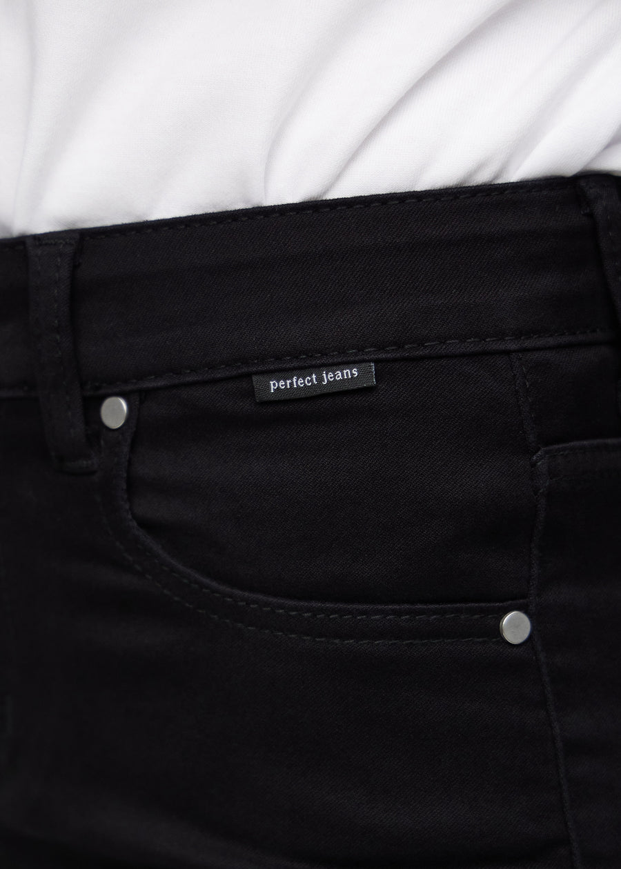 Close-up of black jeans material with the Perfect Jeans logo label at the edge of the front pocket.