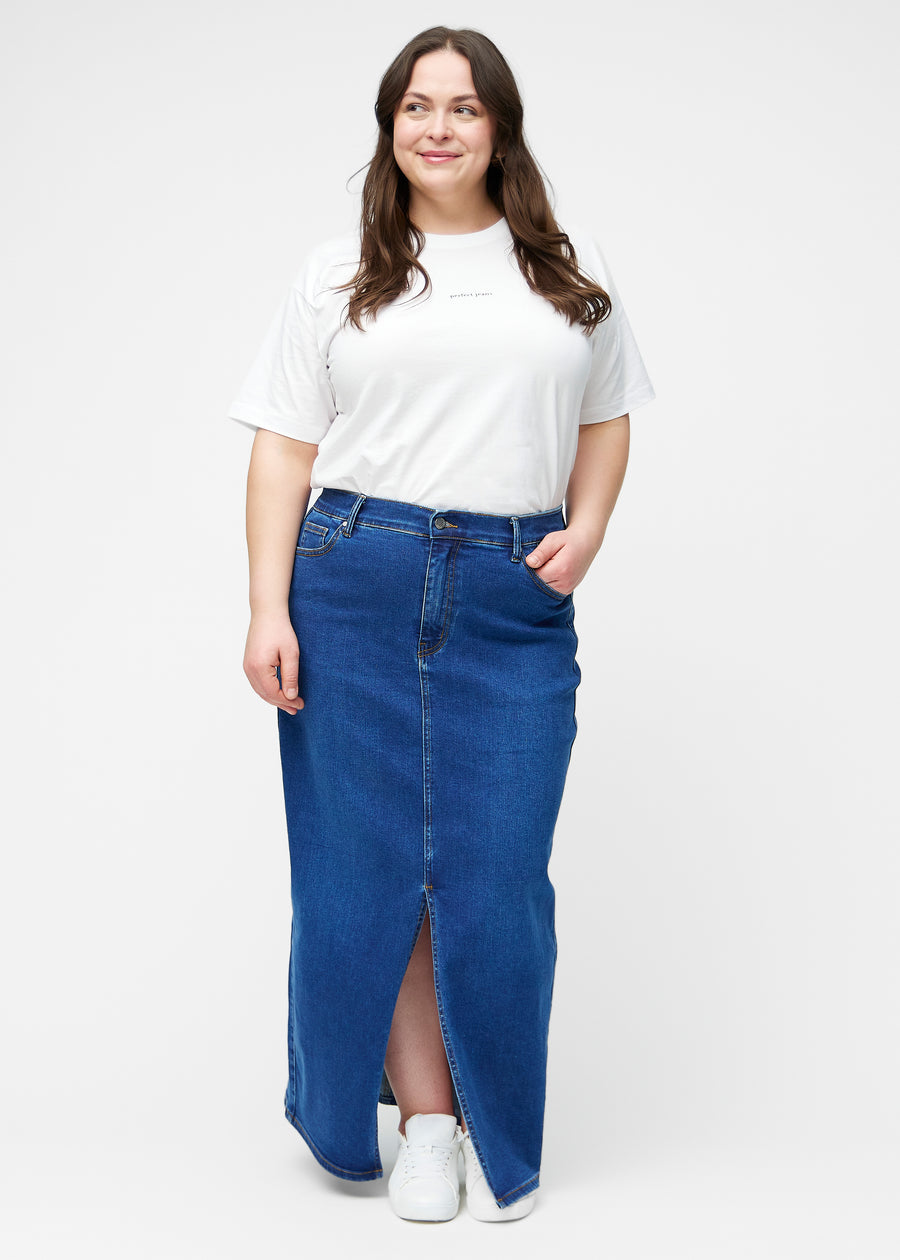 Fuldt billede af plus-size model i lang, mørkeblå denimnederdel i farven Oceans med regulær pasform og slids foran.