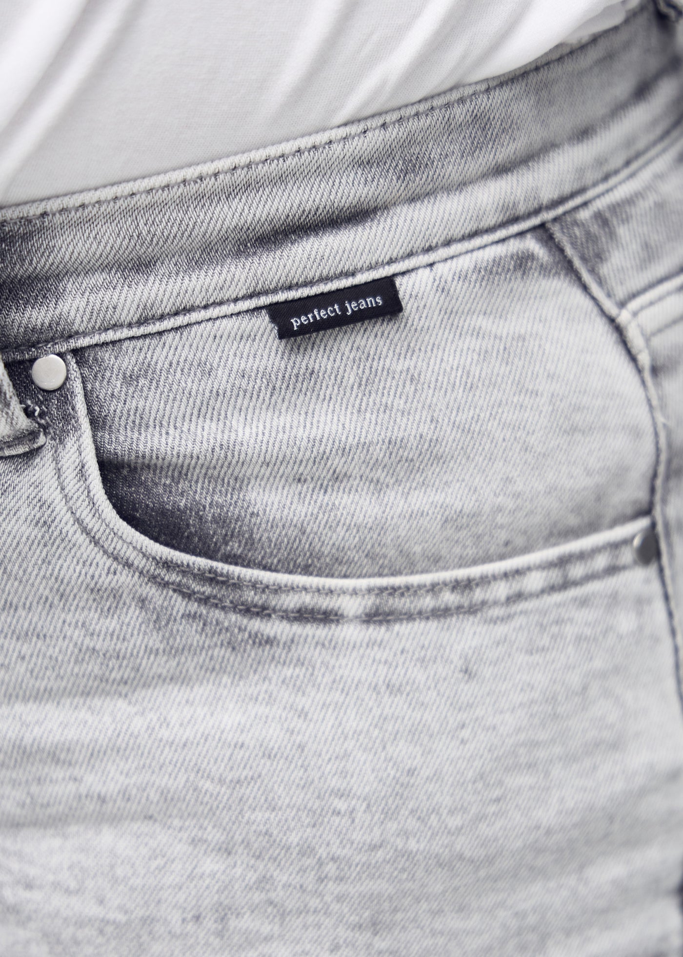 Detaljebillede af forlommen på de lysegrå denim i farven Ashes – logo og snit fremhævet på plus-size model.