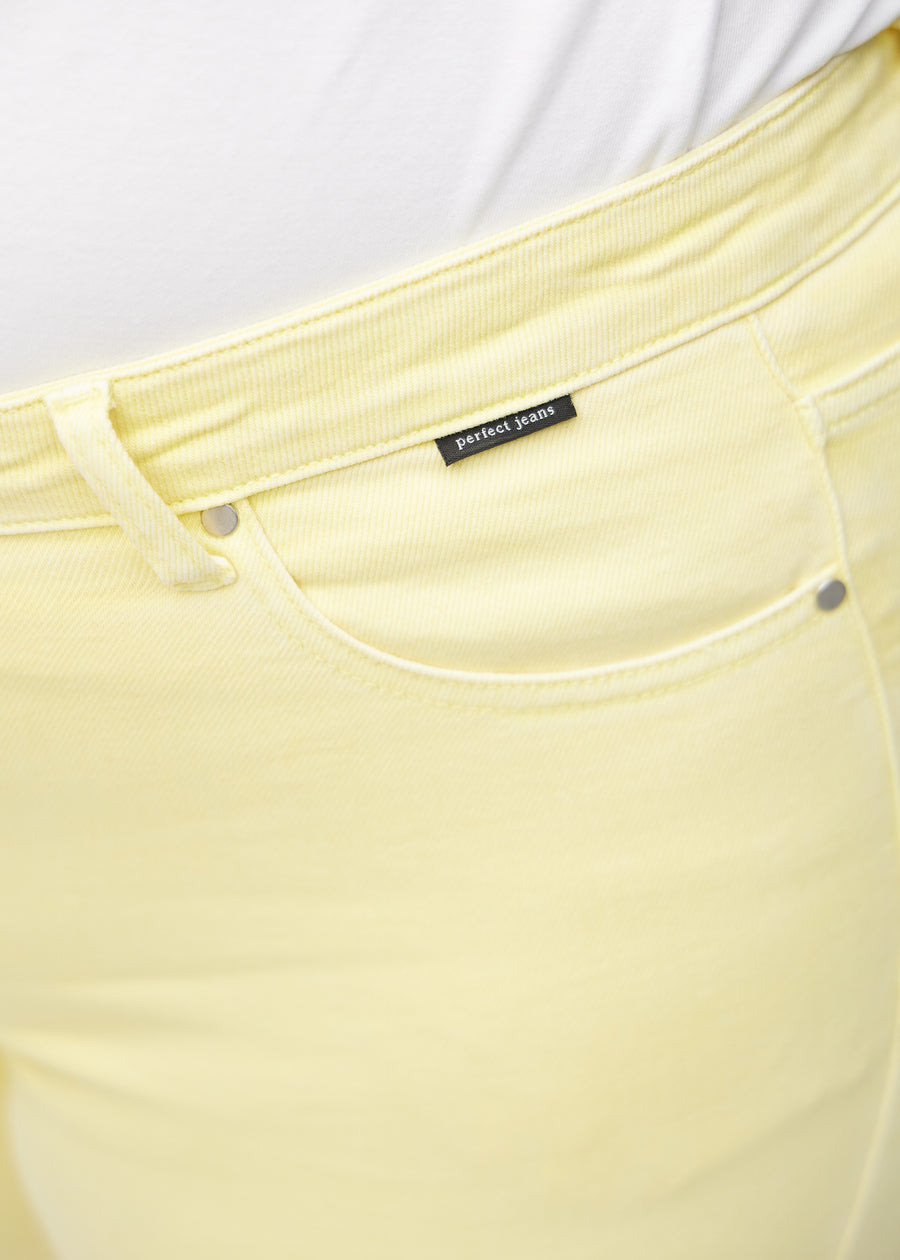 Forlommen på et par lysegule loose jeans, hvor man kan se logoet på en plus-size model.