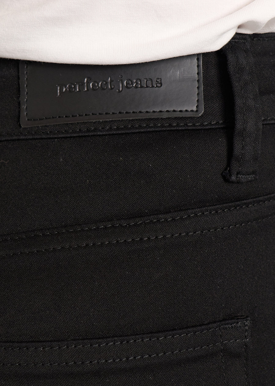 Nærbillede af sort jeansmateriale med Perfect Jeans læderpatch bagpå i taljen.