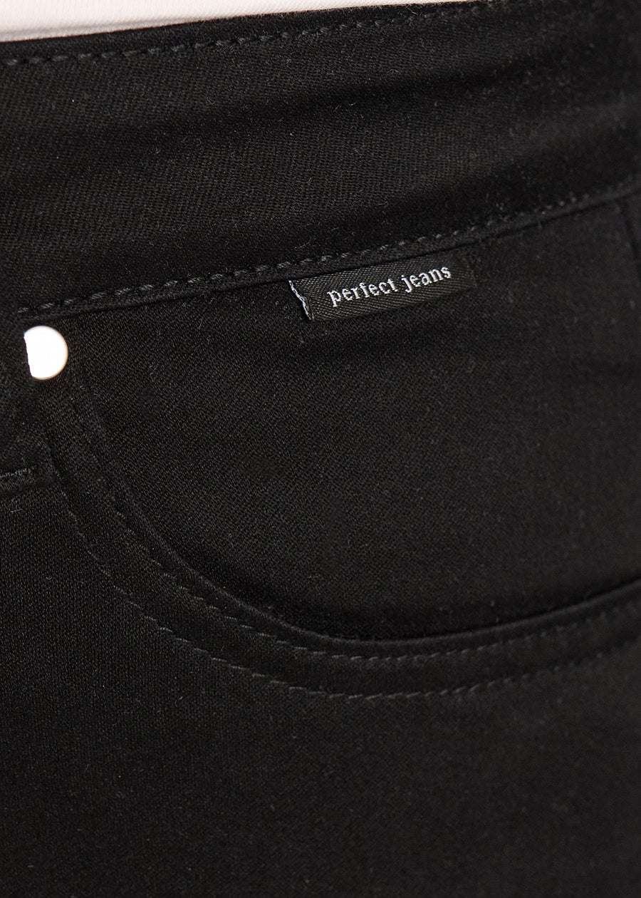 Nærbillede af sort jeansmateriale med Perfect Jeans logoetiket ved forlommekanten, på en plus-size model.