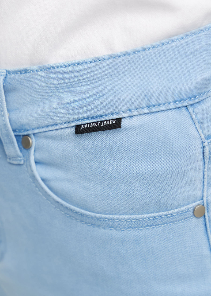 Nærbillede af lyseblåt jeansmateriale med Perfect Jeans logoetiket ved forlommekanten.