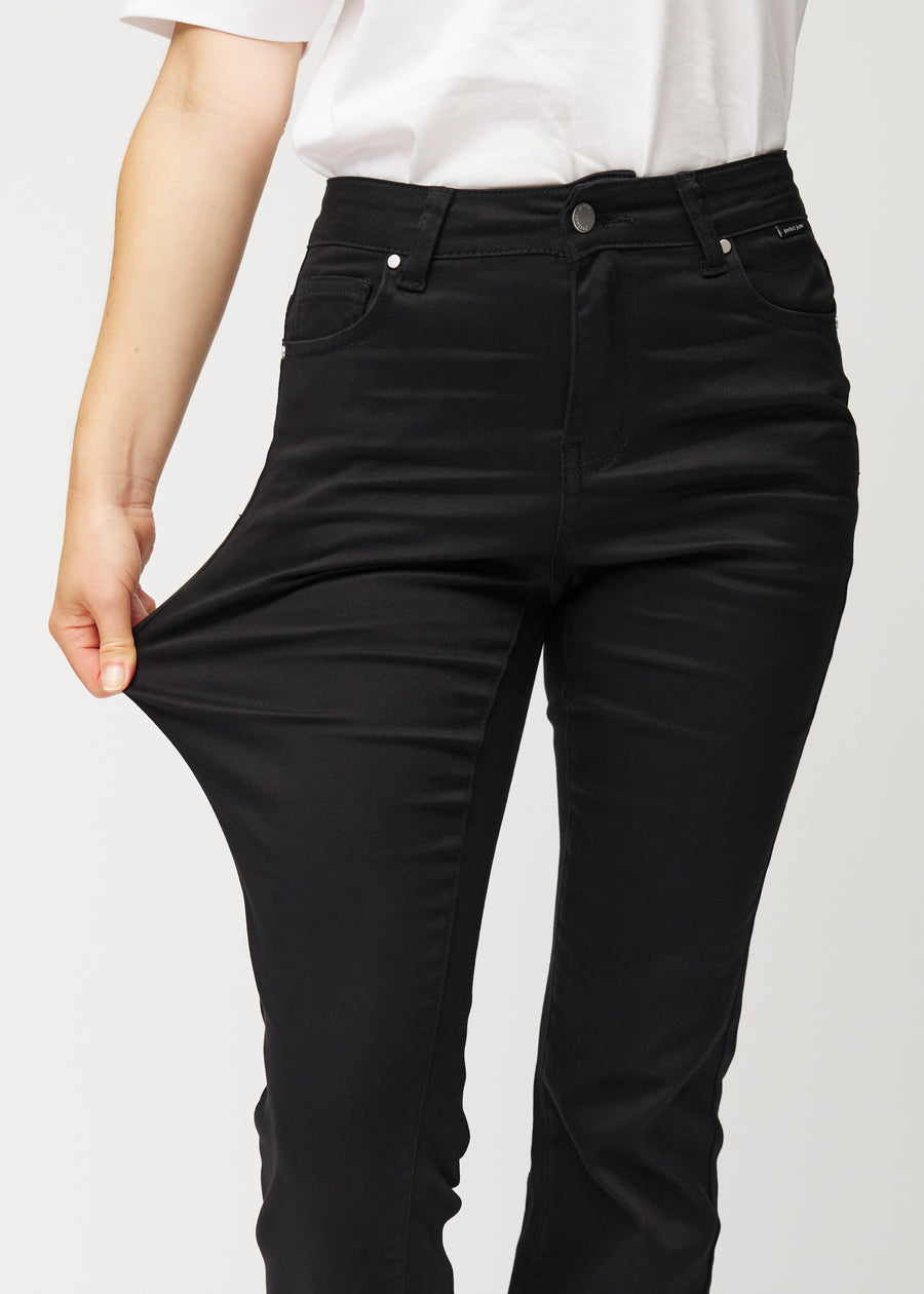 Black mid-rise bootcut jeans in Ravens. A model stretches the jeans at the thigh to show the fabric&