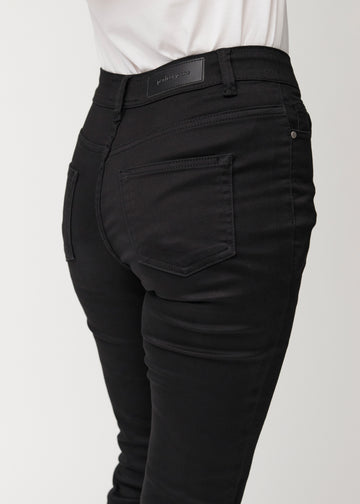 Black mid-rise bootcut jeans in Ravens. Close-up back view on a model, showing the details.