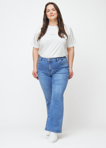 Blue mid-rise bootcut jeans in Rivers. Full-length view of a plus-size model wearing the jeans.
