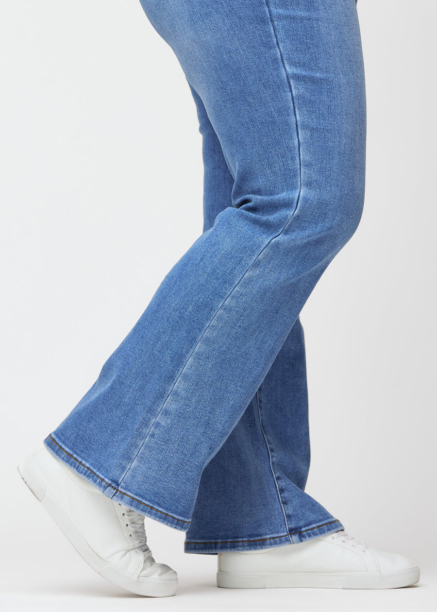 Blue mid-rise bootcut jeans in Rivers. Close-up of the ankle area on a plus-size model, showing the subtle bootcut flare.