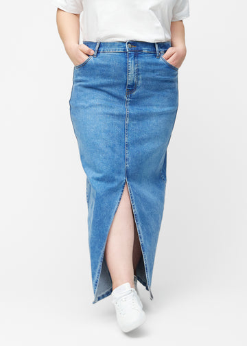 Lang, klassisk blå denimnederdel i farven Rivers med regulær pasform set forfra på plus-size model, med slids foran der starter lige under knæet.
