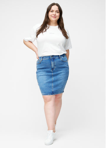 Fuldt billede af plus-size model i klassisk blå, tætsiddende og knælang denimnederdel.