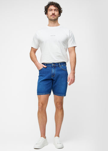 Full image of a model wearing dark blue denim shorts for men in the colour Oceans with a regular fit.