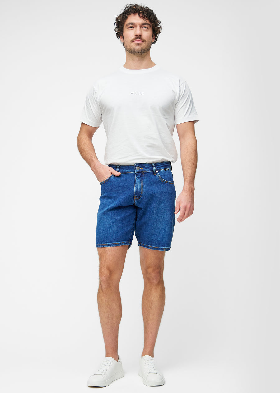 Full image of a model wearing dark blue denim shorts for men in the colour Oceans with a regular fit.