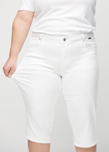 Plus-size model stretches the capris at the thigh to show the stretch.