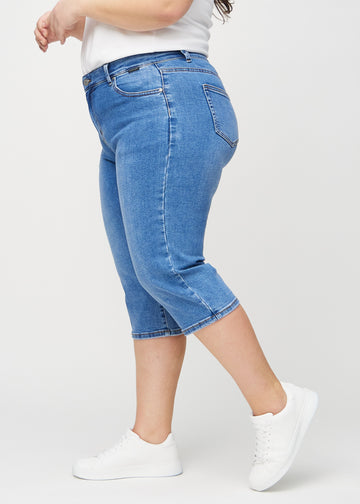 Denim regular capris seen from the side on a plus-size model.