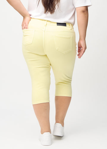 Skinny capris for women in pastel yellow fabric, color Lemonades. Back view on a plus-size model, showing the fit and back pockets.