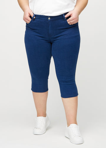 Skinny capris for women in dark blue fabric, color Royals. Front view on a plus-size model, showing the close-fitting legs ending just below the knee.