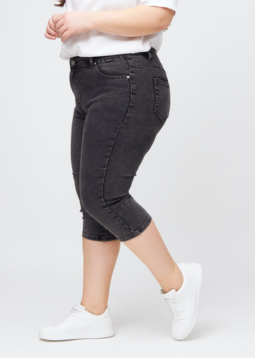 Skinny capris for women in dark grey denim, color Shadows. Side view on a plus-size model, showing the fitted cut.