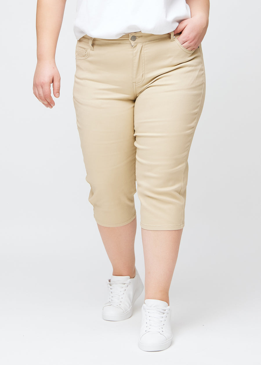 Slim capris for women in beige jeans fabric, color Gazelles. Front view on a plus-size model, showing the fitted cut ending just below the knee.