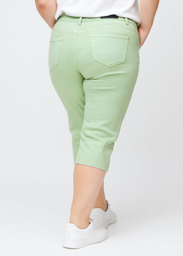 Slim capris for women in pastel light green jeans fabric, color Mints. Back view on a plus-size model, showing the fit, length and back pockets.