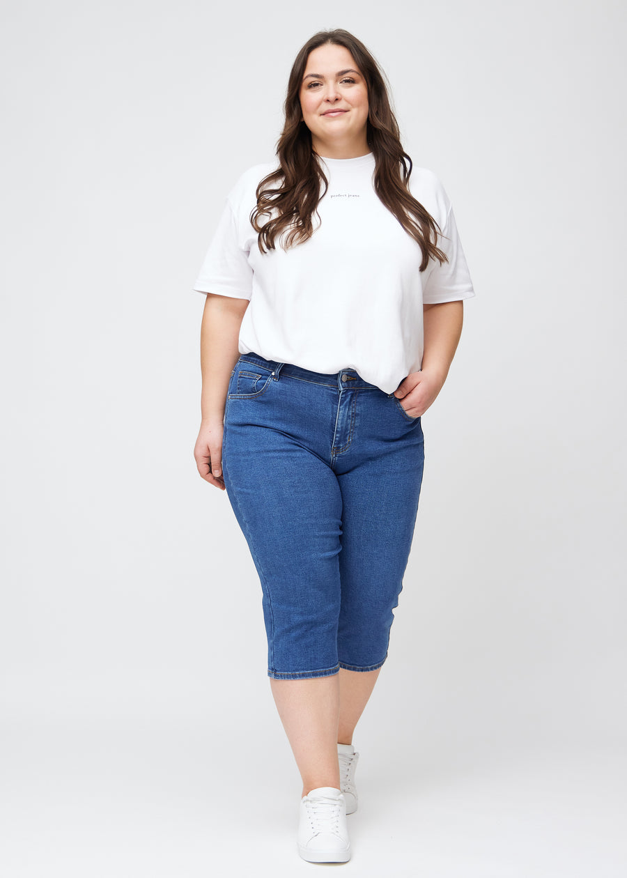 Slim capris for women in dark blue denim, color Oceans. Full-length view of a plus-size model wearing slim capris.