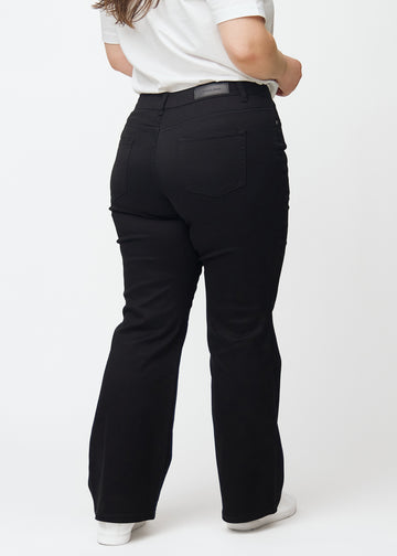 Black mid-rise bootcut jeans in Ravens. Back view on a plus-size model, showing the full fit.