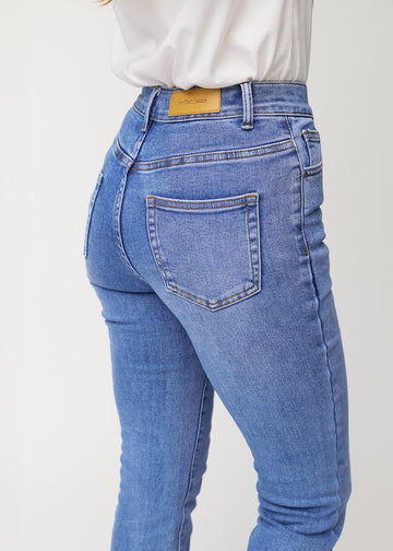 Blue mid-rise bootcut jeans in Rivers. Close-up back view on a model, showing the details.