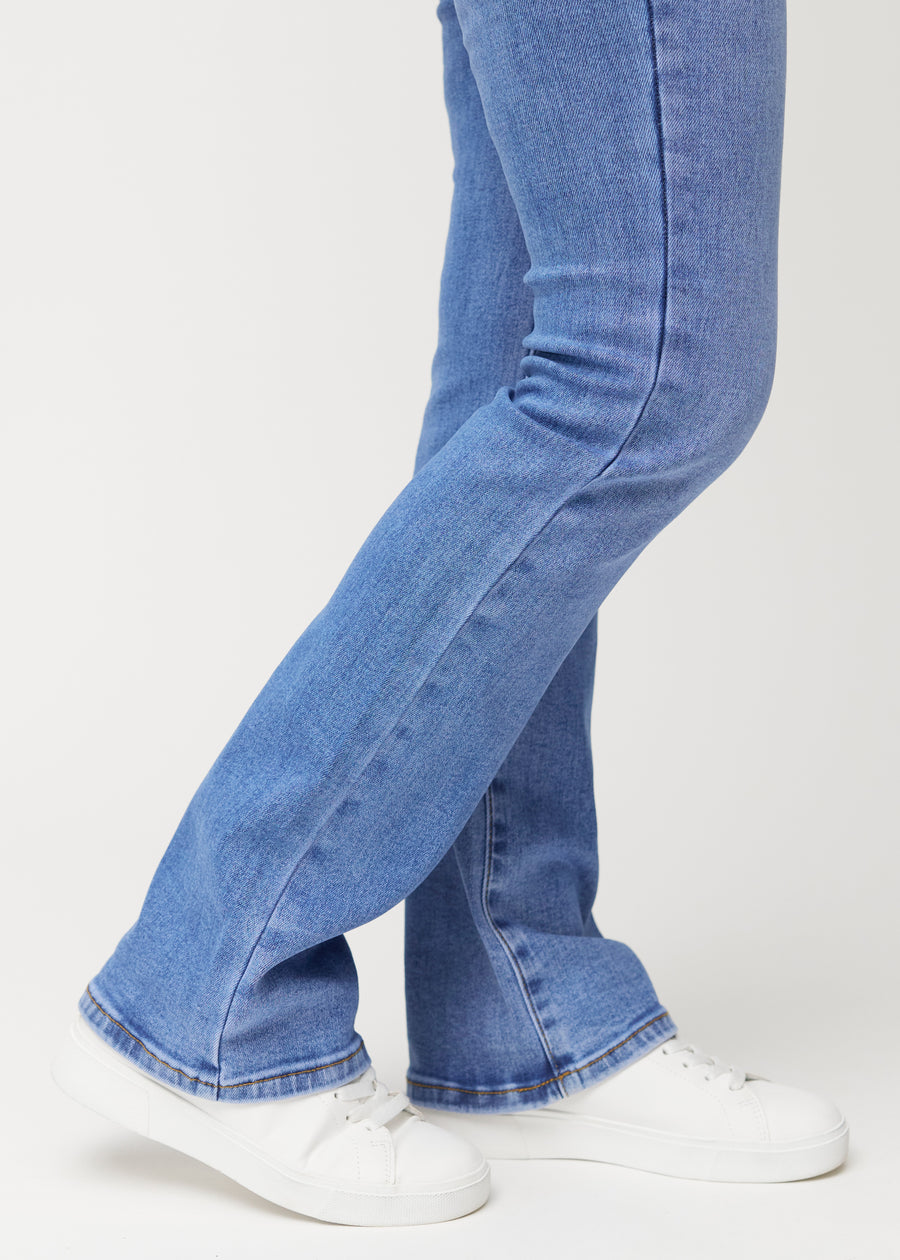 Blue mid-rise bootcut jeans in Rivers. Close-up of the ankle area on a model, showing the subtle bootcut flare.