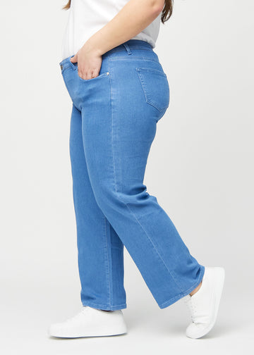 Loose jeans for women in blue, color Geraniums. Side view on a plus-size model, showing the loose fit.