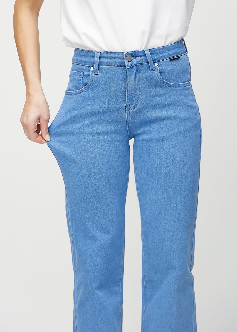 Loose jeans for women in blue, color Geraniums. A model stretches the denim at the thigh to show the fabric&