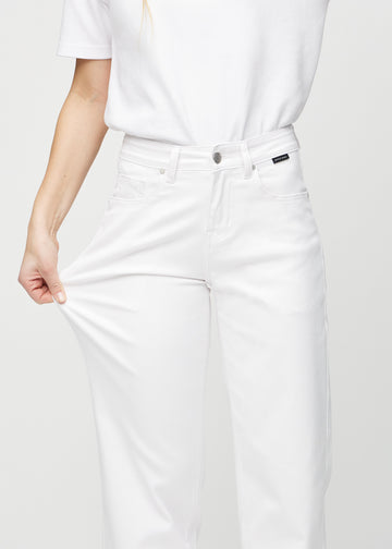 Loose jeans for women in white, color Marguerites. A model stretches the denim at the thigh to show the fabric&
