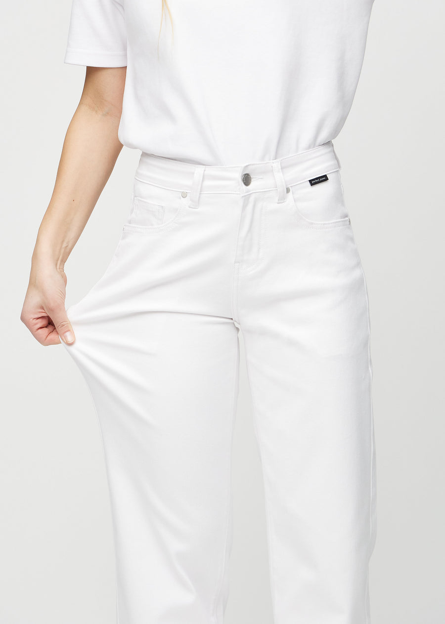 Loose jeans for women in white, color Marguerites. A model stretches the denim at the thigh to show the fabric&