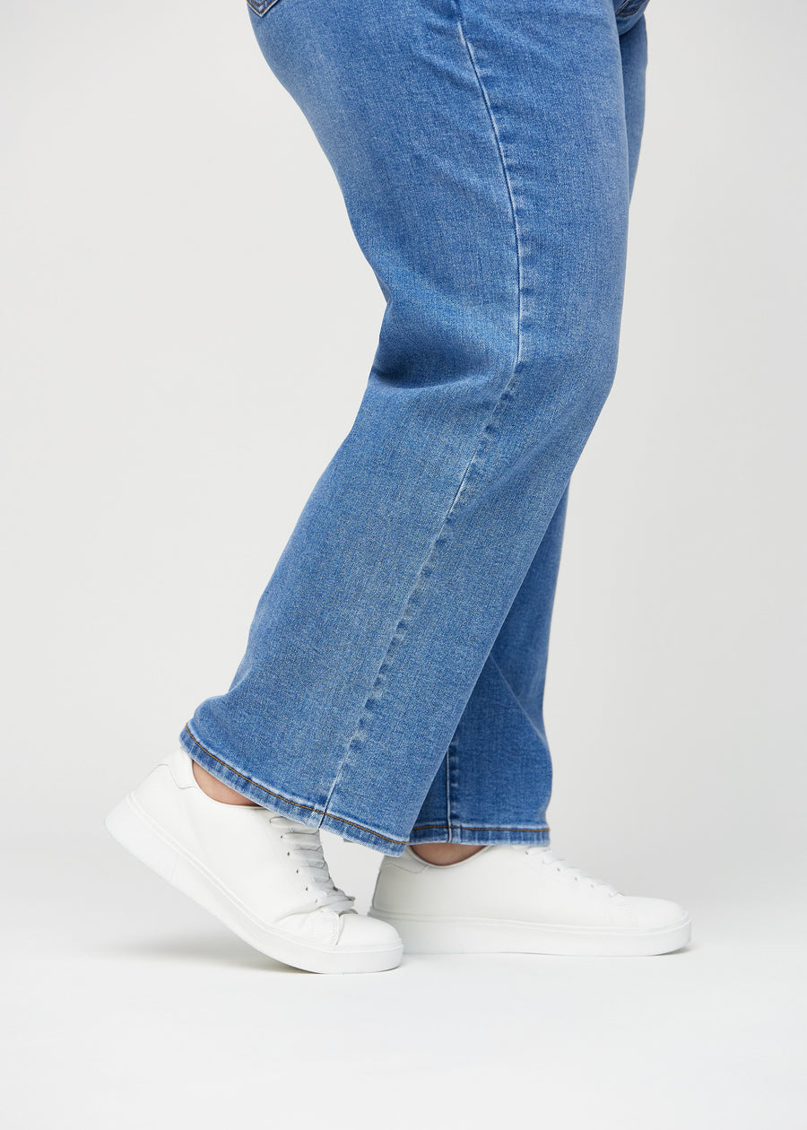 Loose jeans for women in blue, color Rivers. Close-up at the ankles on a plus-size model, showing the wide leg openings.