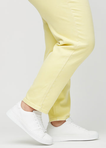 Regular jeans for women in light yellow, color Lemonades. Close-up at the ankles on a plus-size model, showing the straight leg openings.