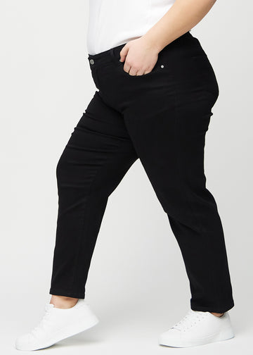 Black regular jeans seen from the side on a plus-size model.