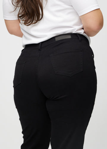Black regular jeans seen from the back close up on a plus-size model to show details.