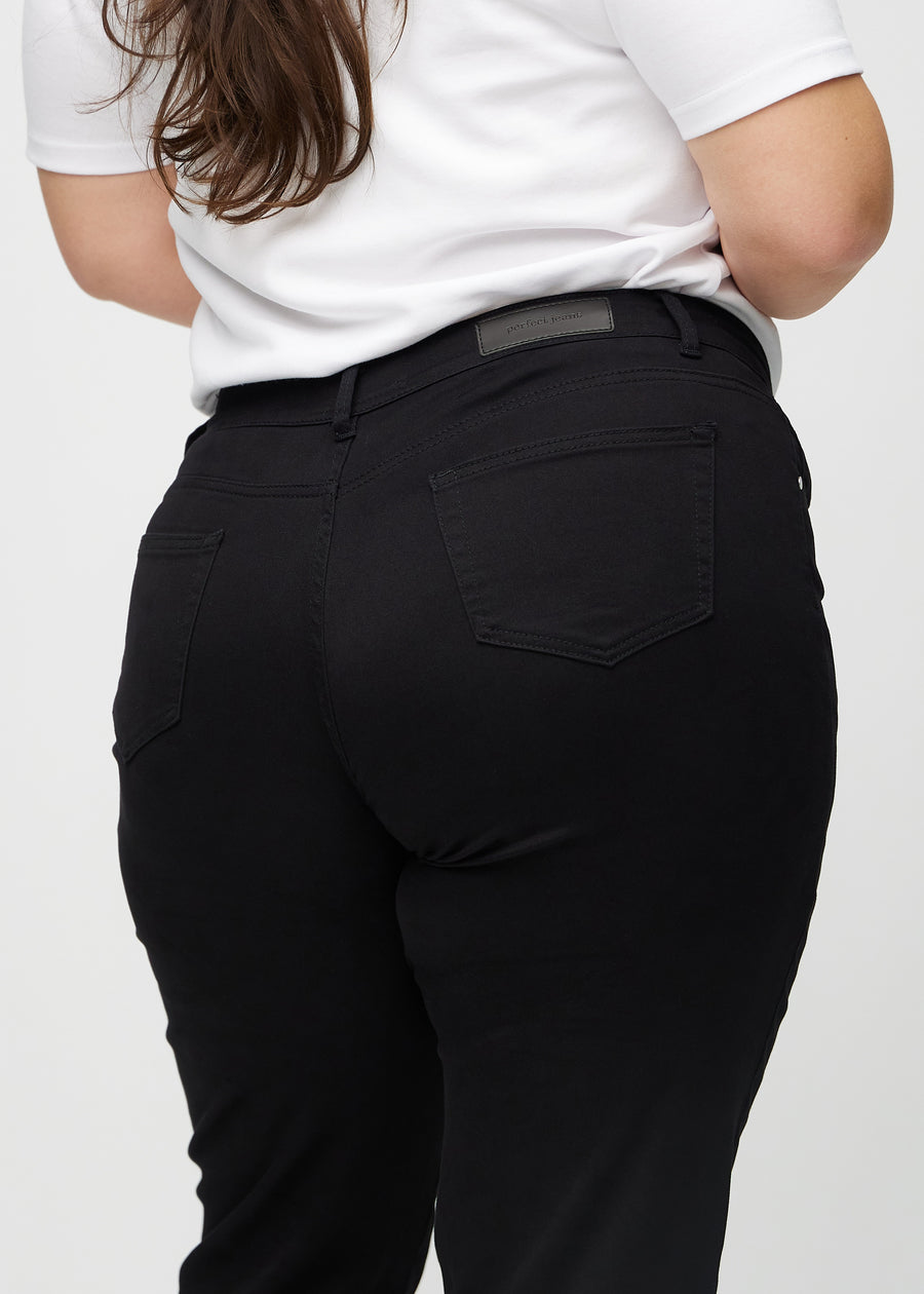 Black regular jeans seen from the back close up on a plus-size model to show details.