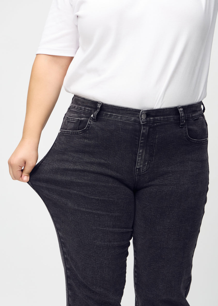 Regular jeans for women in dark grey, color Shadows. A plus-size model stretches the fabric at the thigh to show its stretch.