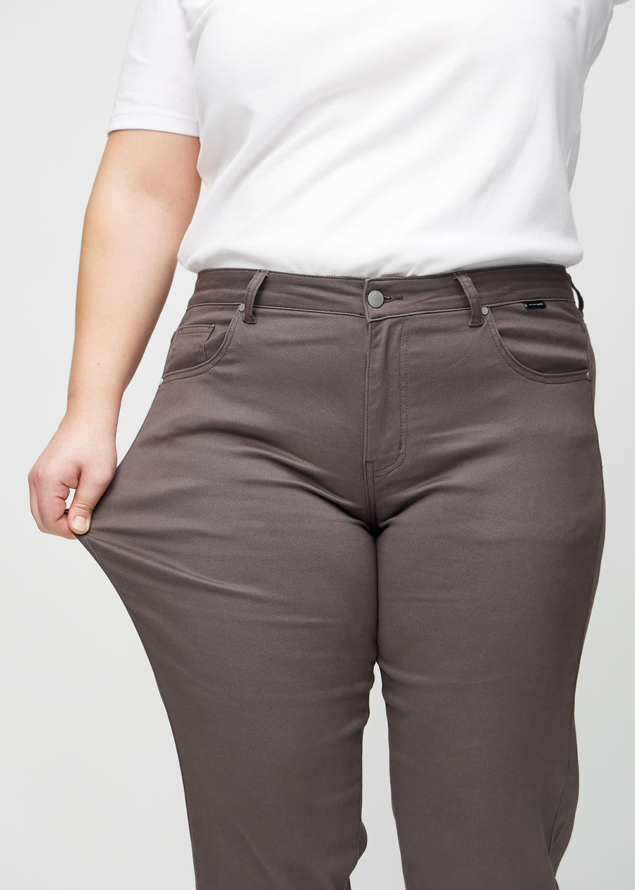 Regular jeans for women in grey-brown, color Thunders. A plus-size model stretches the fabric at the thigh to show its stretch.