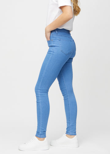 Blue skinny jeans seen from the side on a model.