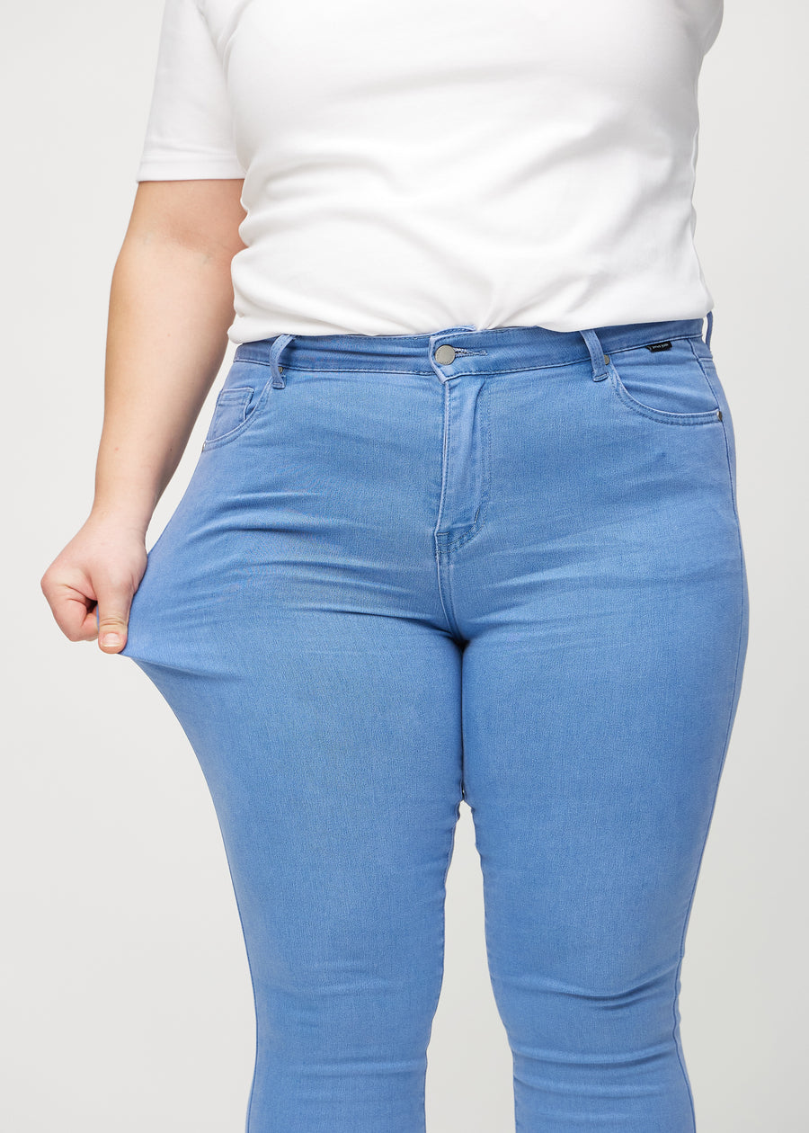 The plus-size model stretches the jeans at the thigh to show the stretch.