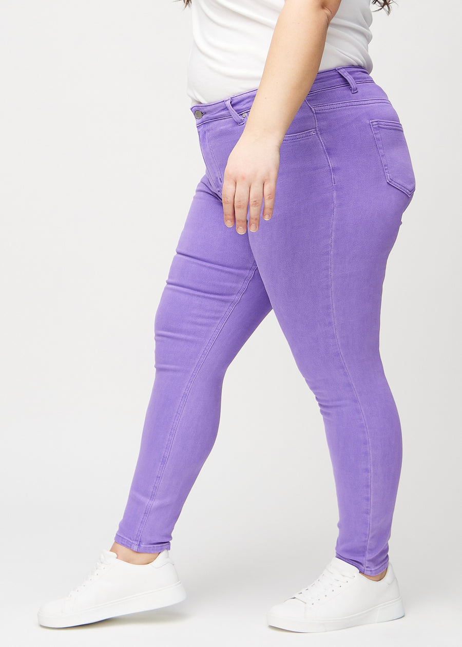 Skinny jeans for women in purple, color Lavenders. Side view on a plus-size model.