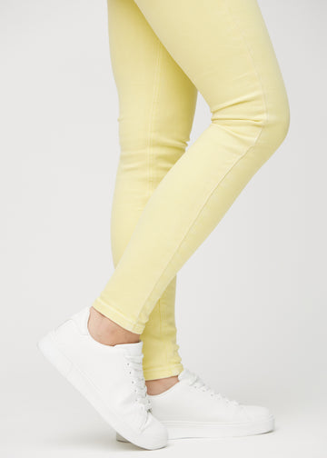 Skinny jeans for women in light yellow, color Lemonades. Close-up of the snug-fitting leg openings at the ankles on a model.
