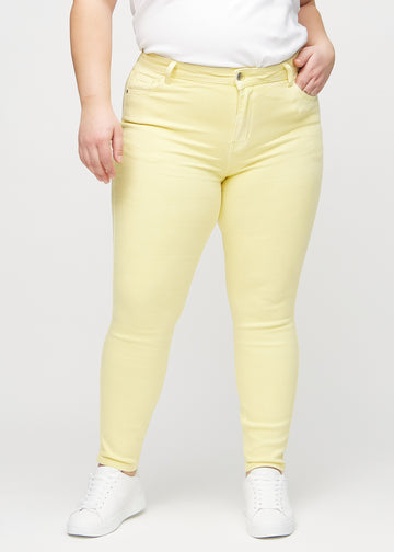 Skinny jeans for women in light yellow, color Lemonades. Front view on a plus-size model, showing the close fit through the legs.