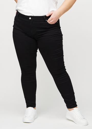 Black skinny jeans, model name Ravens, with a close fit through the leg on a plus-size model, seen from the front.