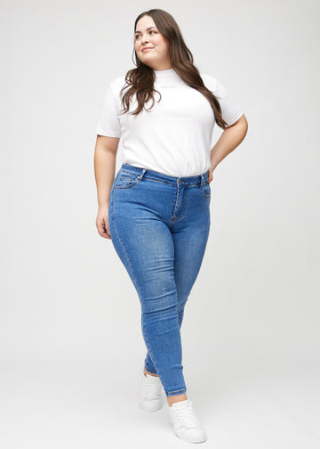 Skinny jeans for women in blue, color Rivers. Full-length view of a plus-size model in the jeans.