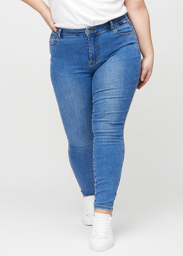 Skinny jeans for women in blue, color Rivers. Front view on a plus-size model, showing the close fit through the legs.