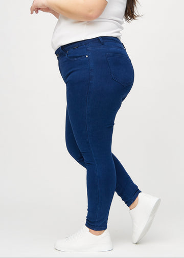 Skinny jeans for women in dark blue, color Royals. Side view on a plus-size model.