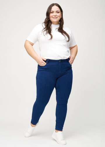 Skinny jeans for women in dark blue, color Royals. Full-length view of a plus-size model wearing the jeans.