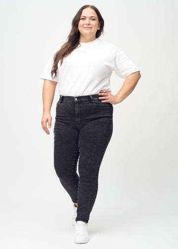 Skinny jeans for women in dark grey, color Shadows. Full-length view of a plus-size model in the jeans.