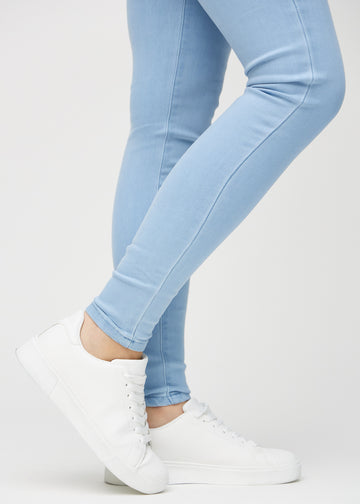 Skinny jeans for women in light blue, color Skies. Close-up at the ankles on a model, showing the close-fitting leg openings.